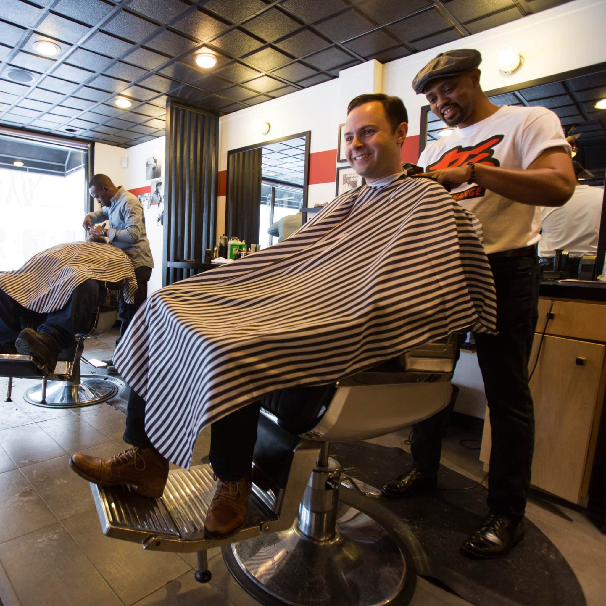 Jake Sturgis, owner of Captivate Media, smiling, getting a haircut in a barbershop.