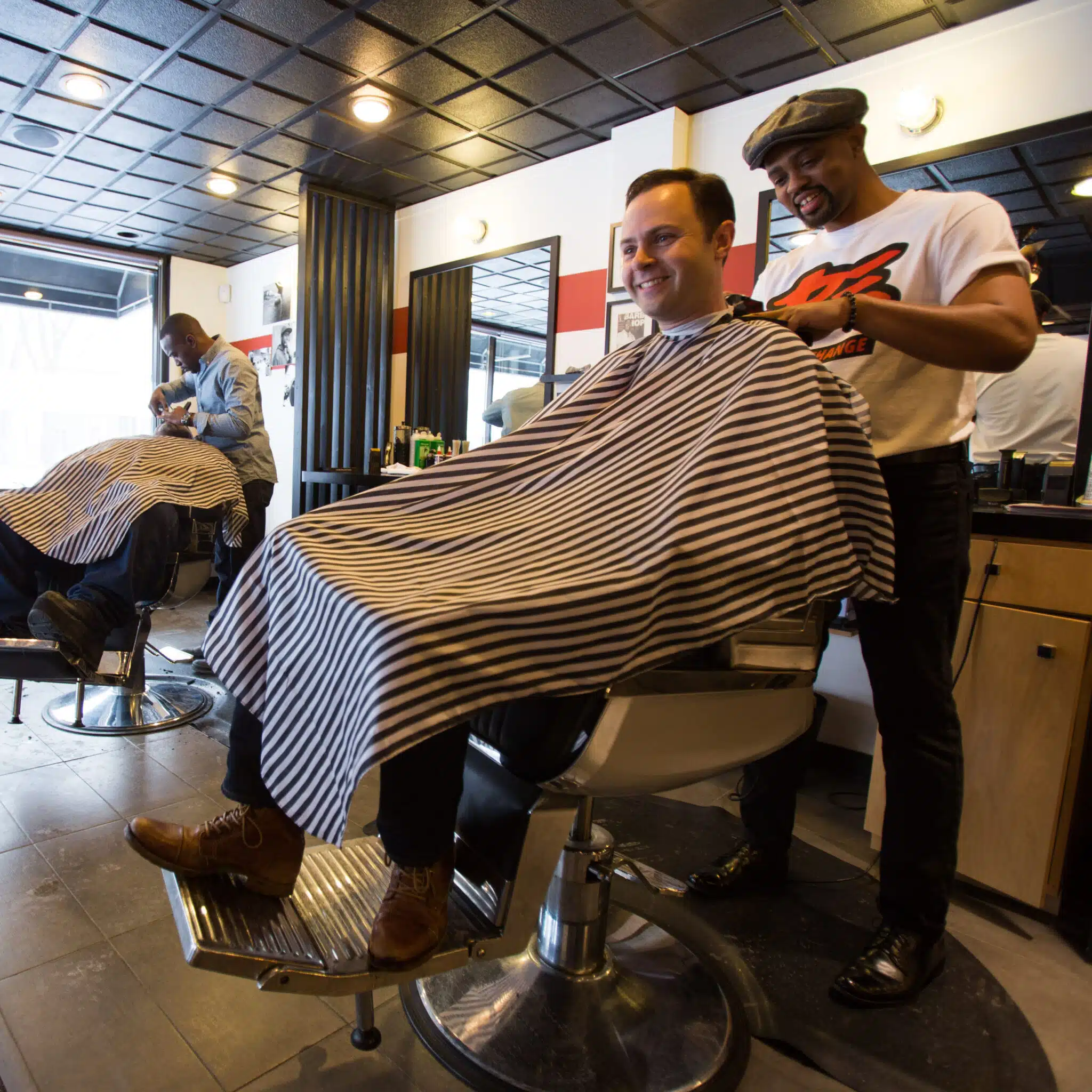 Jake Sturgis, owner of Captivate Media, smiling, getting a haircut in a barbershop.