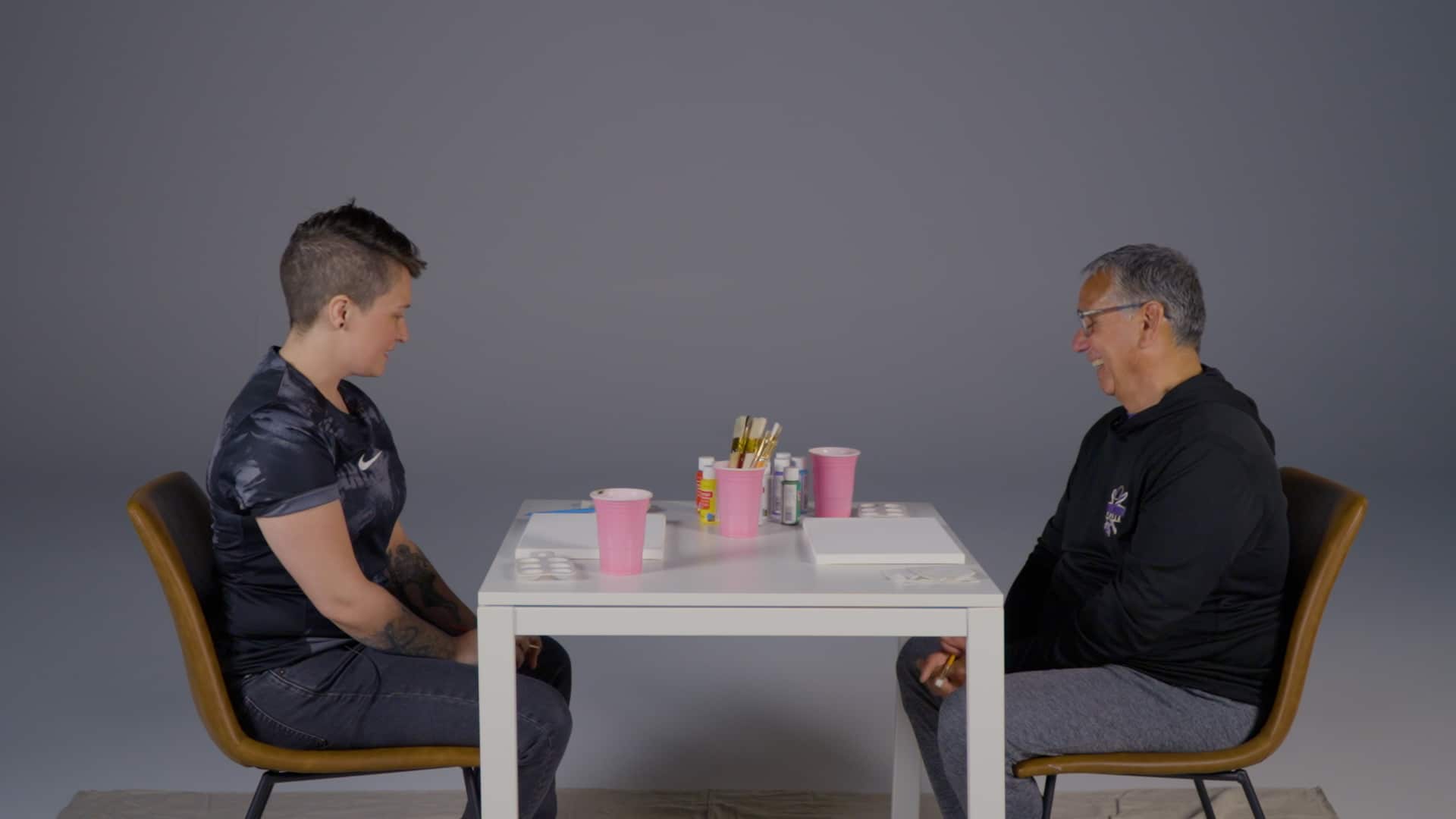 Staff sitting across a small table, preparing to chat and paint