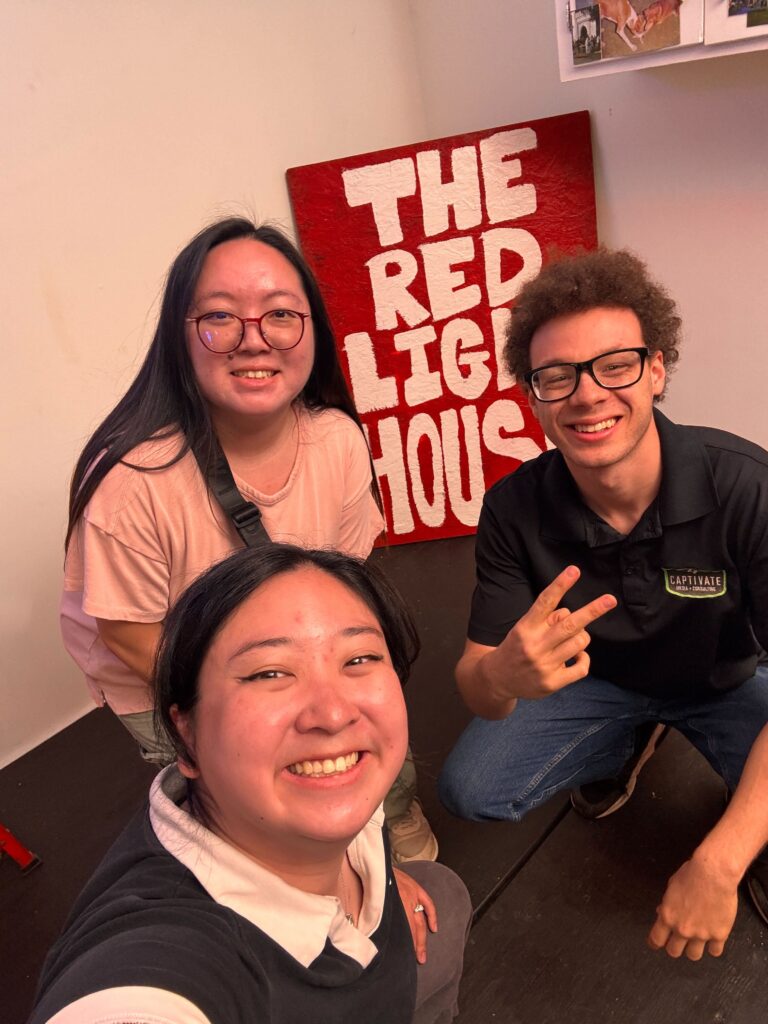 three people posing in front of a red poster