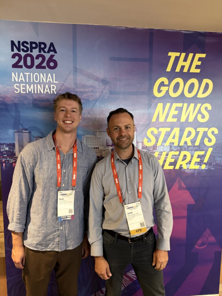 two men smiling at a conference