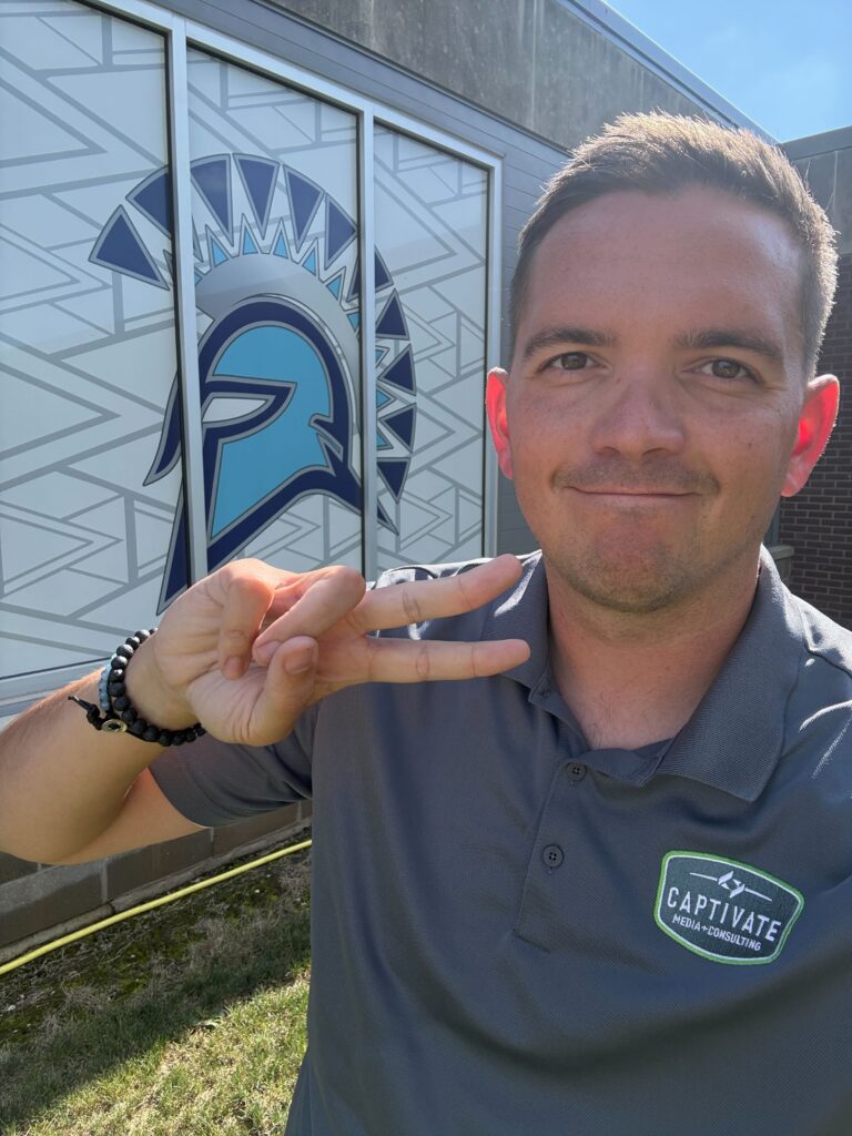 man smiling in front of a trojan logo