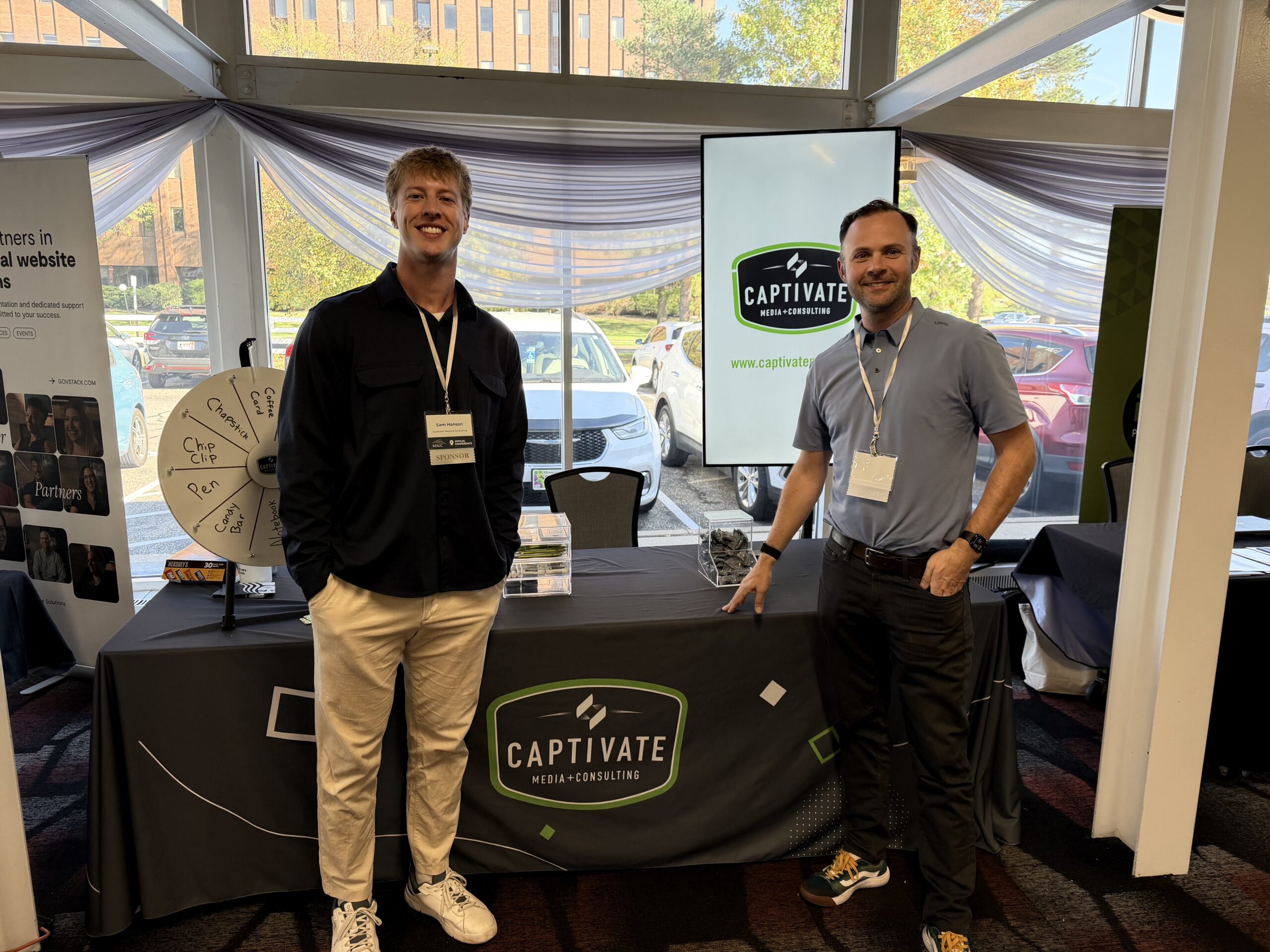 two men smiling in front of a captivate branded booth